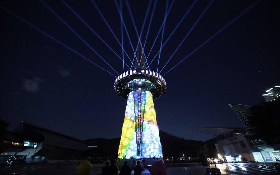 A tower is lit up in the park.