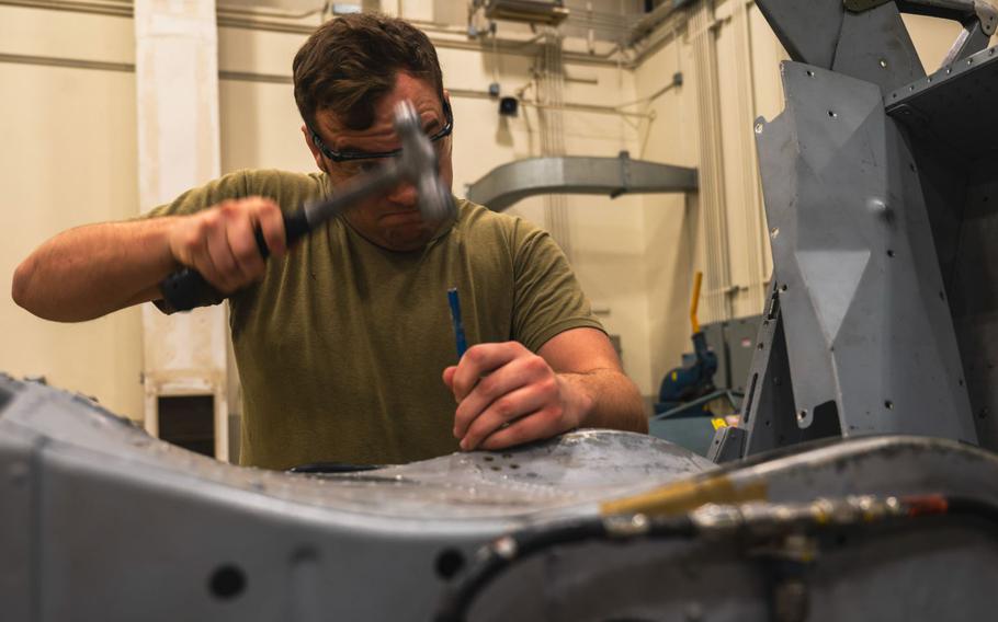 U.S. Air Force Staff Sgt. Nathan Frank is using hammer in order to replace rivets.