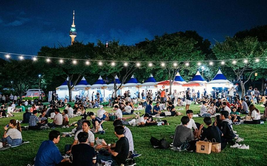 Visitors are enjoying chicken and beer on the lawn at night.