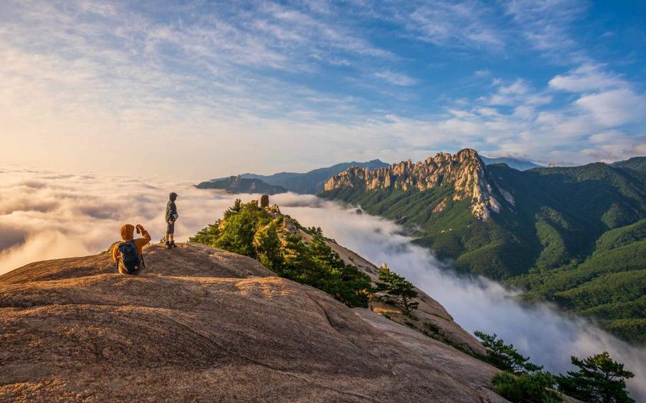 Hikers take pictures with Ulsanbawi Rock of Seoraksan Mountain in the distance.