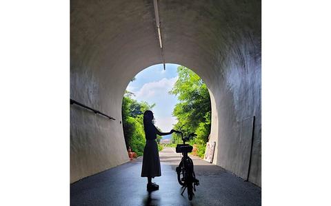 Photo Of A woman with her bike inside a tunnel. 