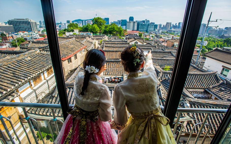 Two women with traditional costumes are enjoying the scenery from a building.