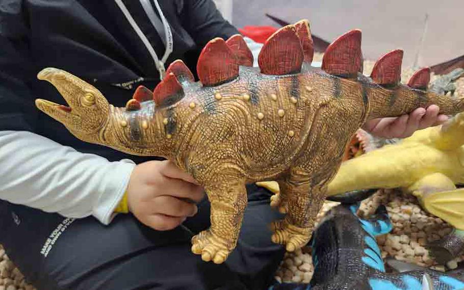 A child holding a dinosaur miniature toy