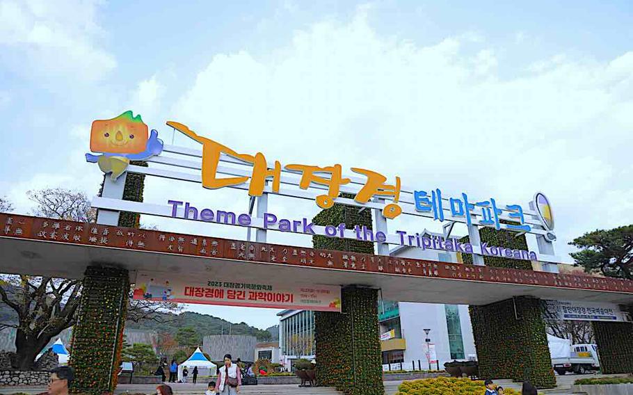 Some visitors are walking or taking photos in front of the entrance of Theme Park of the Tripitaka Koreana