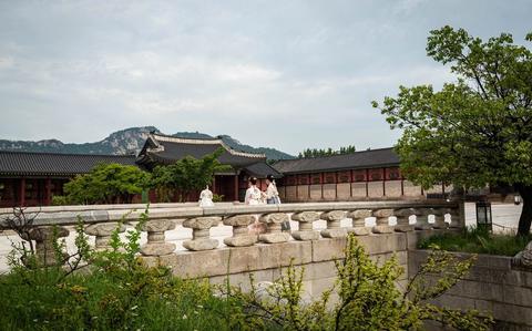 Photo Of Women dressed in historic attire walk through the grounds at Gyeongbokgung Palace in Seoul, Korea.