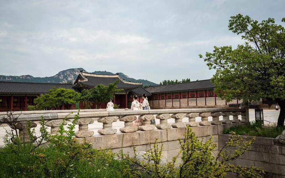 Women dressed in historic attire walk through the grounds at Gyeongbokgung Palace in Seoul, Korea.