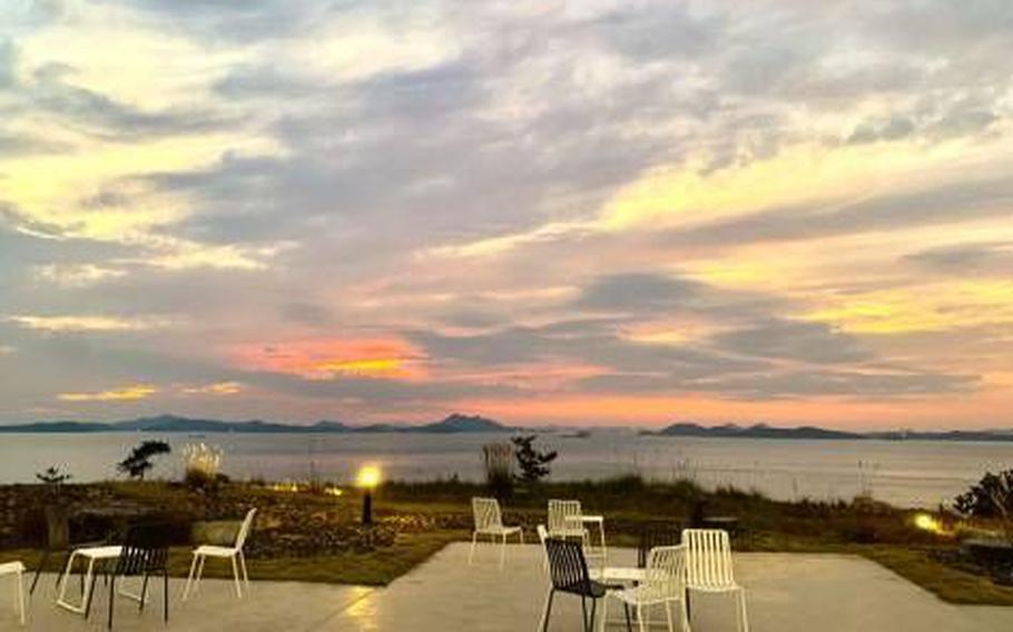 there are some chairs. the ocean and some small islands can be seen.