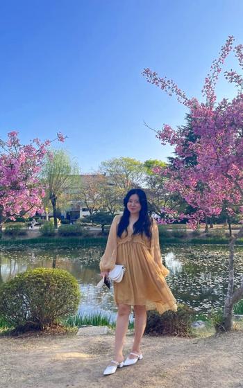 Hyemin posed for a photo in front of cherry blossoms.