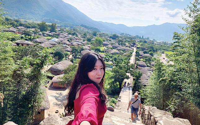 Hyemin is taking a photo of herself and Nakan Eupseong Folk Village.