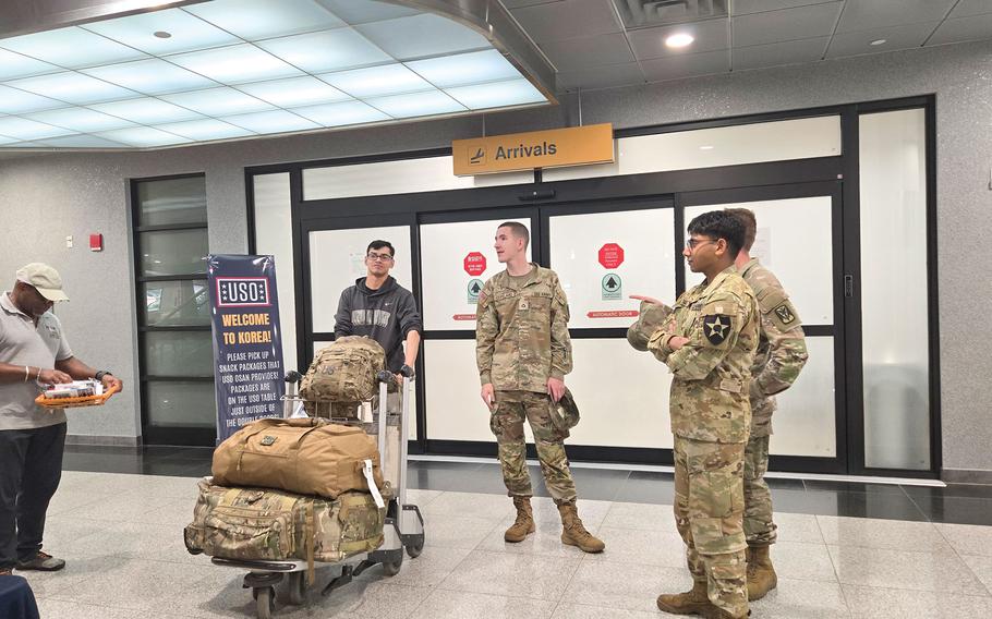 Some people stand in front of the Arrivals gate.