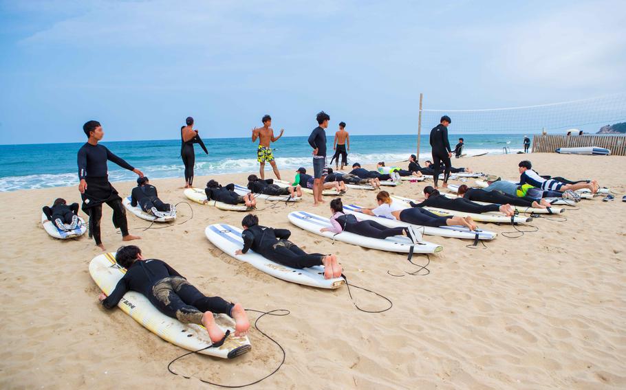 Participants are being trained for surfing on the beach.