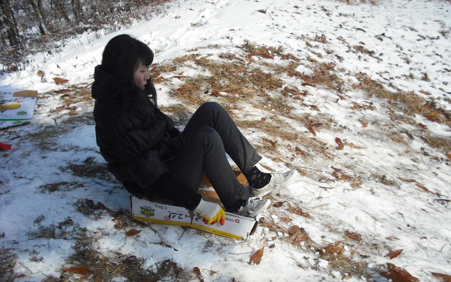 My sister sleds down the snowy hill in my grandmother’s backyard.