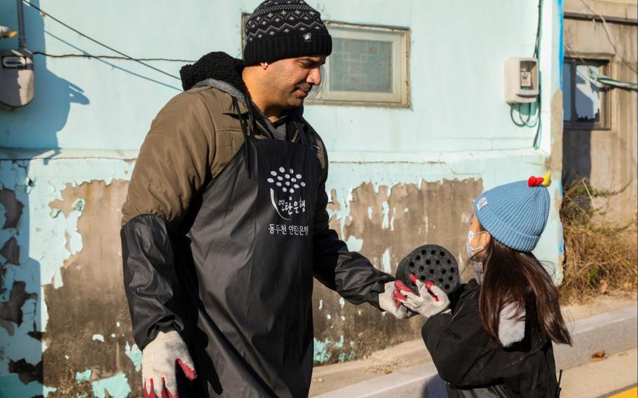 U.S. Army Staff Sgt. Miguel Bermejo gives a coal briquette to a child in the neighborhood of Sangpae, Dongducheon city.