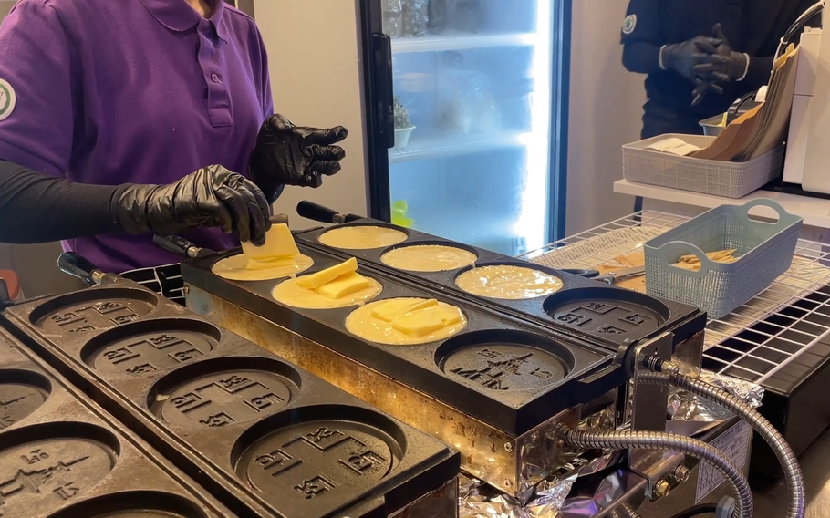 A staff member makes 10-won Cheese Breads.