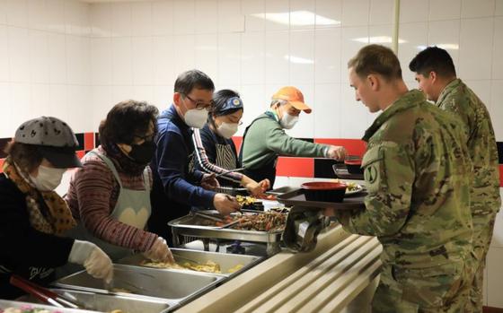 Photo Of U.S. Soldiers are served traditional Korean food during a Lunar New Year meal. two soldiers and five volunteers are in photo.