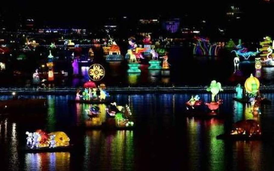 Some boats light up in the river.