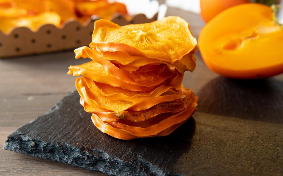 Dried persimmon on a stand on a wooden kitchen table.