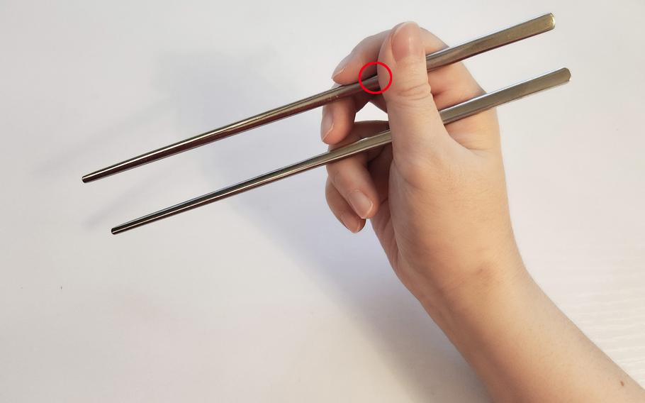 Grab the second chopstick between the index and middle finger and hold it with the thumb.