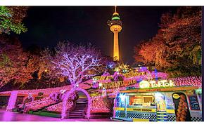 illuminated E-World. food booth and tower can be seen.