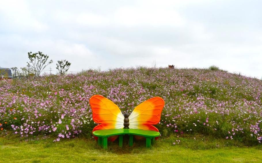 flowers are blooming behind a butterfly-shaped bench.