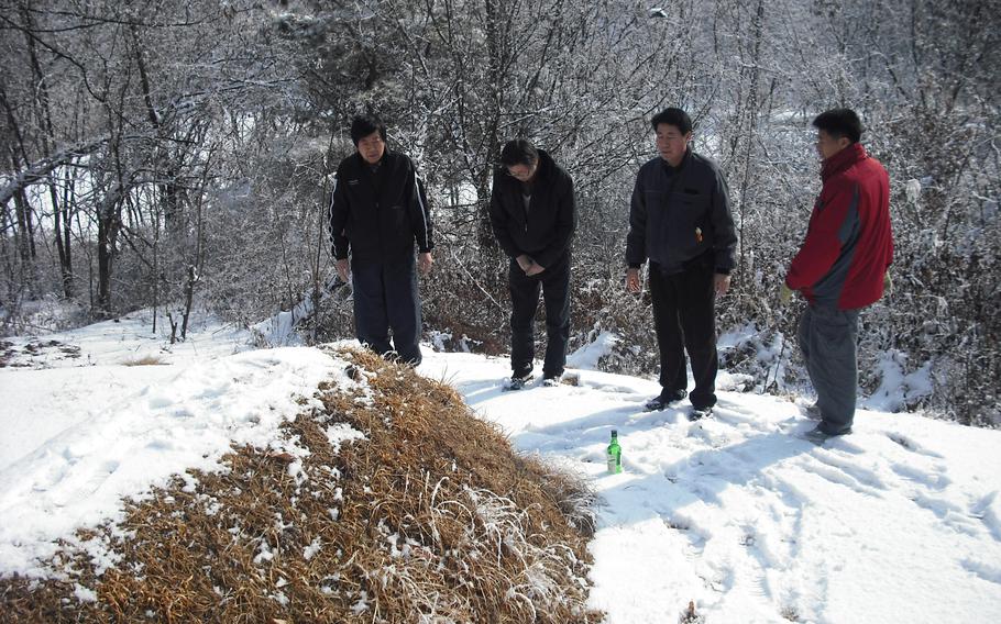 My dad and uncles greet one of our ancestors before cleaning snow on the grave mounds on the mountain.