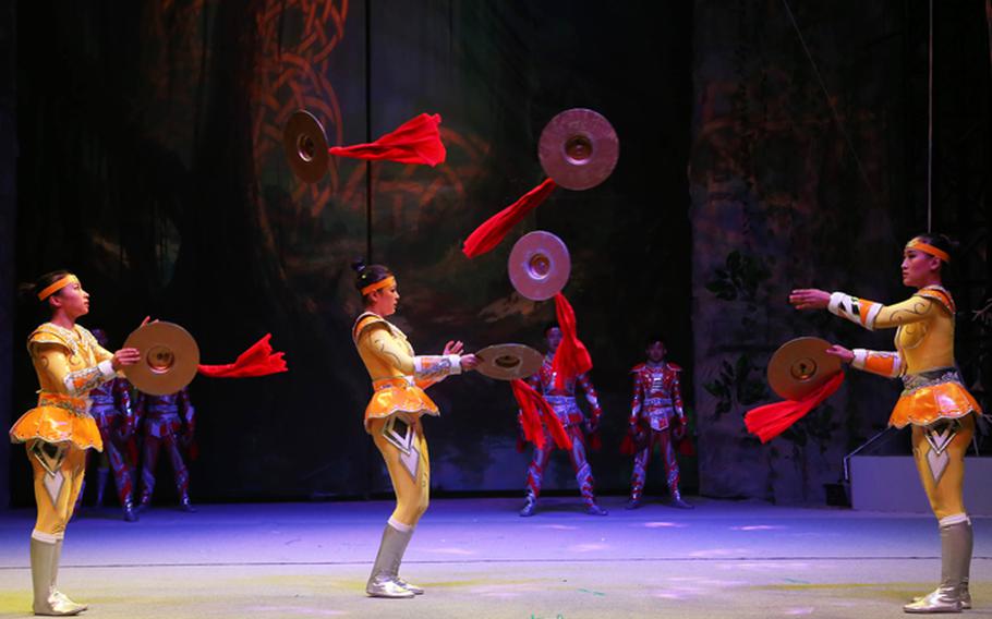 circus members are thowing and catching cymbals each other as performance.