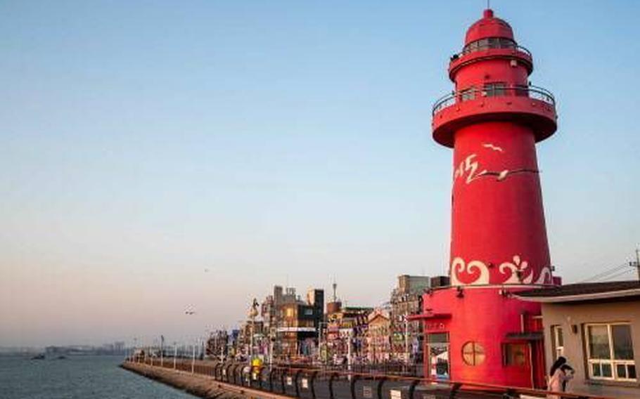A lighthouse can be seen by the sea.