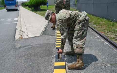 Photo Of Airman 1st Class Jayden Bolo, 8th Maintenance Squadron aircraft metals technology journeyman, uses a specially fabricated hook to install a custom built railroad track cover they created at Kunsan Air Base.