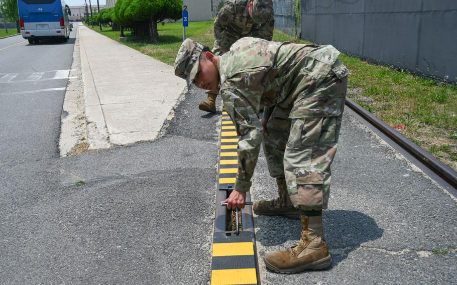 Airman 1st Class Jayden Bolo, 8th Maintenance Squadron aircraft metals technology journeyman, uses a specially fabricated hook to install a custom built railroad track cover they created at Kunsan Air Base.