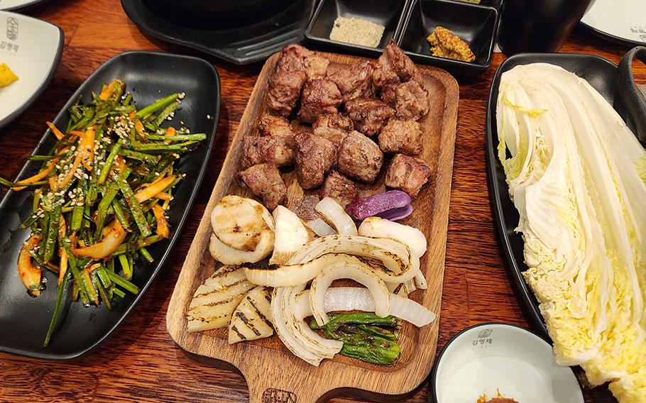  Grilled meat and table setting. uncooked Chinese cabbage, frilled meats and onions on the dishes.