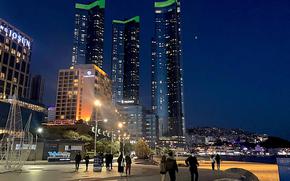 People walk by the beach in Busan at night.