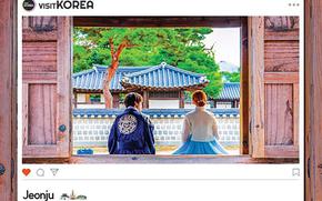 A couple in Korean traditional clothes sit.