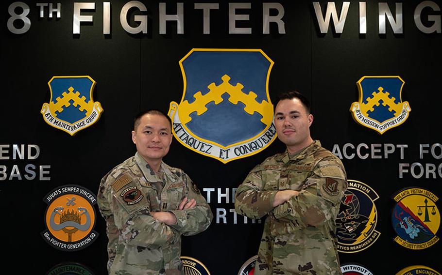 Capt. Denny Yang, 8th Fighter Wing protocol officer in charge, left, and Tech. Sgt. Jamin Solomon, 8th FW protocol NCO in charge, right, stand in front of a heritage wall at Kunsan Air Base, Republic of Korea, Jan. 4, 2023. The 8th FW protocol team is responsible for managing and coordinating distinguished visitor tours, changes of command and other events held on base. (U.S. Air Force photo by Staff Sgt. Isaiah J. Soliz)