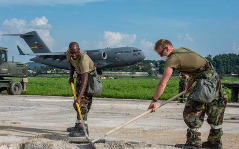 Photo Of U.S. Air Force Staff Sgt. Connor Stevens, left, 51st Civil Engineer Squadron structural engineer, and Staff Sgt. Hayden Brooks, 51st CES structural engineer, conduct rapid airfield damage repair while a C-17 Globemaster III lands。