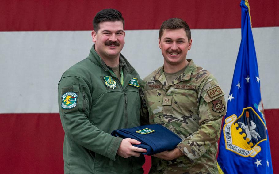 U.S. Air Force Capt. Sean Ryan, 25th Fighter Squadron pilot, presents Staff Sgt. Connor Hoffman, 25th Fighter Generation Squadron, with a patch and coveralls during the 25th FGS Dedicated Crew Chief Ceremony at Osan Air Base, Republic of Korea, Dec. 19, 2023. DCCs are presented with a coin, certificate and patch to be worn on their uniforms to commemorate their achievements. (U.S. Air Force photo by Senior Airman Trevor Gordnier)