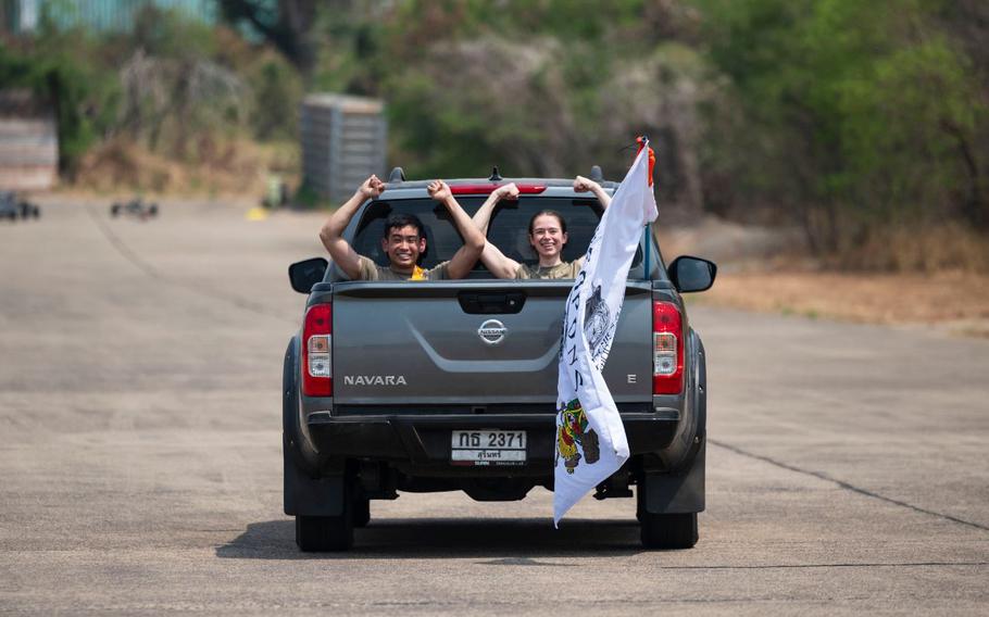 Airman 1st Class Darren Ky, left, and Senior Airman Ashley Taylor, both 80th Fighter Generation Squadron aircraft armament systems, perform a gesture of squadron pride while transitting to conduct maintenance on an F-16 Fighting Falcon during Joint Exercise Cobra Gold 24 at Korat Royal Thai Air Force Base, Kingdom of Thailand, Feb. 29, 2024. The 43rd iteration of the exercise brought together service members from seven nations Feb. 26 - March 9, to enhance regional security by improving warfighting readiness and speed of response. 