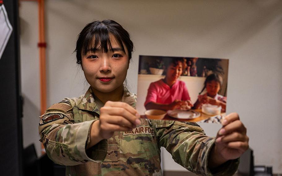 Airman 1st Class Hyeon Jung, 8th Communications Squadron cybersecurity technician, holds up a photo of her making rice cakes with her mother when she was a child during Chuseok in the Republic of Korea at Kunsan Air Base, ROK, Sept. 26, 2023. Chuseok is a holiday in which families come together and celebrate the harvest as well as honor their ancestors. (U.S. Air Force photo by Staff Sgt. Samuel Earick)