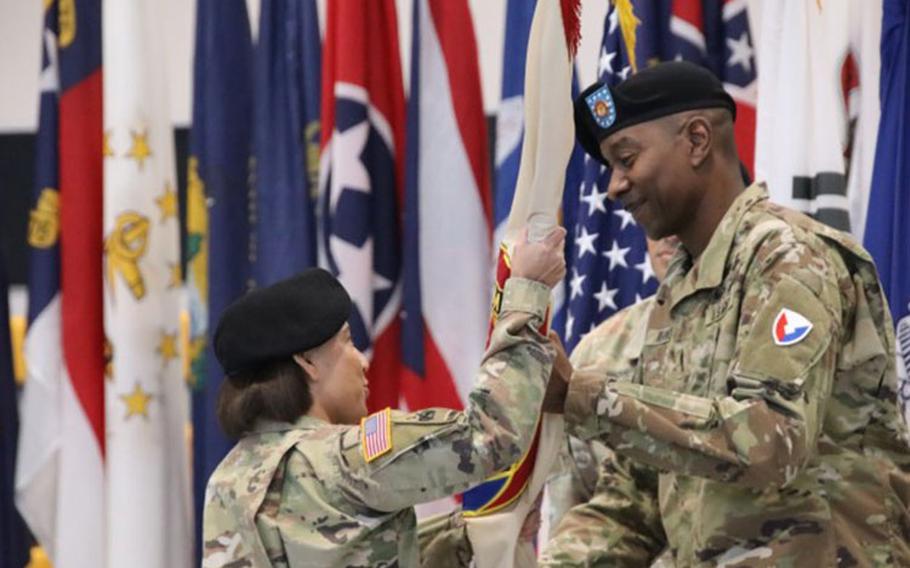 Command Sgt. Maj. Christopher Reaves, 403rd Army Field Support Brigade command sergeant major, passes the unit colors to Col. Lisa Rennard, brigade commander, 403rd AFSB, for the final time during his relinquishment of responsibility ceremony at the Kelly Fitness Center on Camp Walker, South Korea, May 16. (Photo Credit: Galen Putnam)