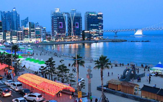 Gwangalli Beach with buildings and a bridge at night.