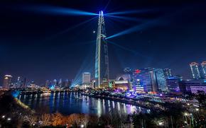 Lotte World Tower at night. A pond can be seen beside the tower.