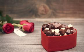 there are some roses and a heart-shaped box with chocolates on the table.