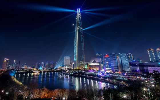 Lotte World Tower at night. A pond can be seen beside the pond.